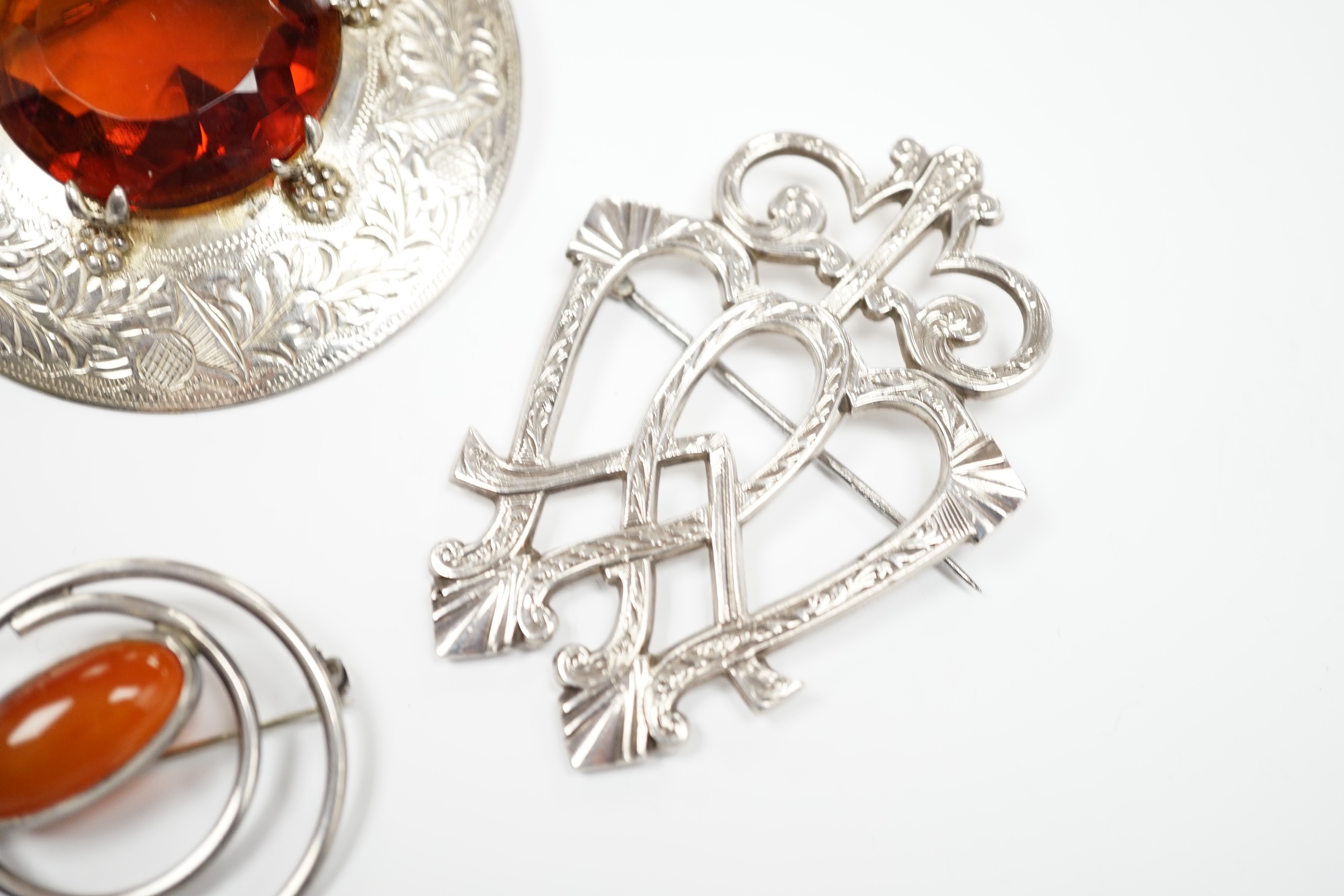 A 1950's Scottish silver and citrine coloured paste set circular brooch, 68mm, an Edwardian silver Celtic style brooch and three other white metal brooches, including Scottish hardstone set.